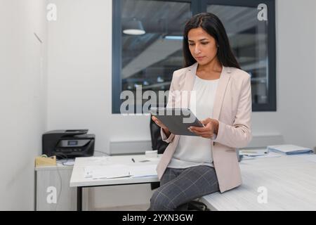 Indian businesswoman in a company office, working on a tablet. Business and managers concepts. Stock Photo