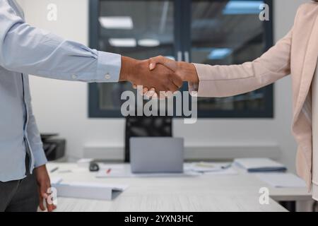 Excited African American job candidate entering the meeting office, warm shaking hands with an Indian female manager. Recruitment concept. Stock Photo