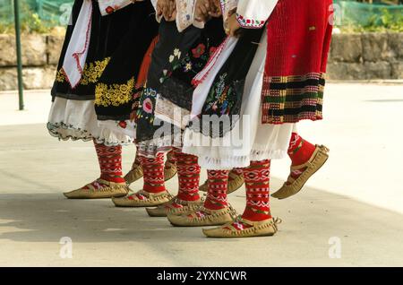 Bulgarian folklore. Girls dancing folk dance. People in traditional costumes dance Bulgarian folk dances. Close-up of female legs with traditional sho Stock Photo