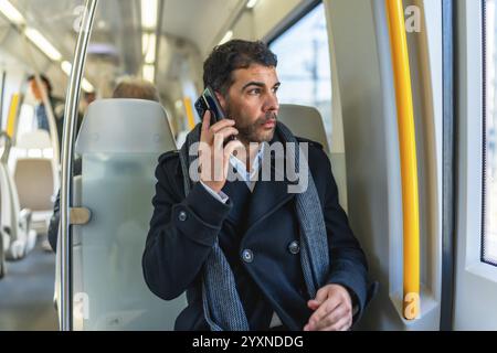 Handsome serious caucasian businessman looking through the window while talking to the mobile sitting on the metro Stock Photo