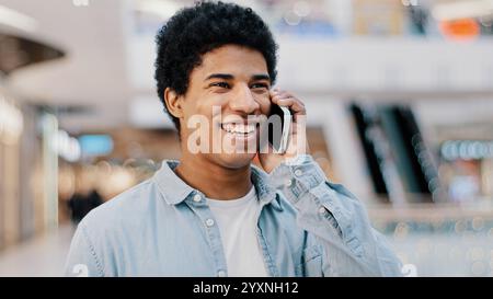 Close-up african guy looking at mobile phone answering unexpected call talking to girlfriend family smiling laughing chatting on cellphone remote Stock Photo