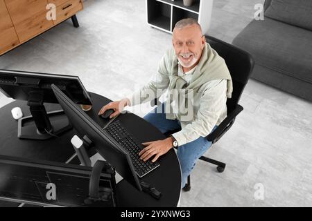 Mature programmer working with computer at table in office, top view Stock Photo