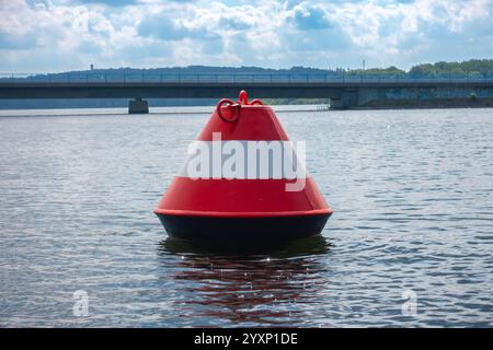 A red and white buoy sits in the water. The buoy is on a bridge over a body of water Stock Photo