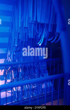A blue and white striped wall with a blue tarp hanging from it. The tarp is hanging from the wall and he is a part of a larger installation Stock Photo