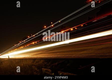 A long train track with a bright light shining on it. The light is creating a long streak of light that is almost as long as the train Stock Photo