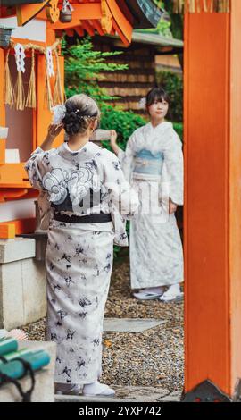 Kyoto, Japan - 05.07.2024: Two asian women wearin traditional japanese yukata kimono at Fushimi Inari Shrine. Stock Photo