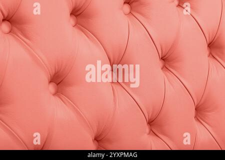 Close up background texture of coral pastel pink capitone genuine leather, retro Chesterfield style soft tufted furniture upholstery with deep diamond Stock Photo