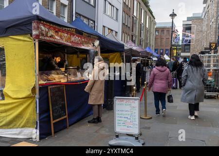 London, UK - December 3, 2024, A woman buys chicken kebab from a vendor at a street food market selling Lebanese cuisine. Stock Photo