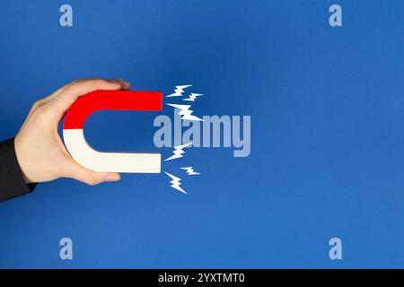 Woman holding horseshoe magnet with lightnings on blue background, closeup. Space for text Stock Photo