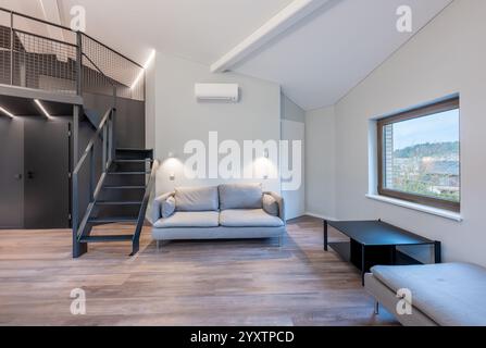 Spacious and bright minimalist living room featuring a loft, modern furniture, and natural light. A warm and inviting space for relaxation with beauti Stock Photo