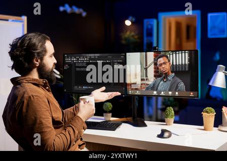 IT developer working from home in remote videocall with BIPOC coworker, testing programs and systems. Programmer checking code with colleague in internet videoconference meeting Stock Photo
