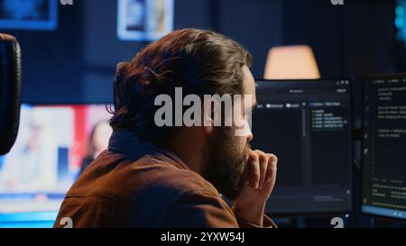 Developer overthinking solutions while doing programming during remote job shift in home office. IT admin working on computer in apartment late at night, thinking how to fix bugs, camera A close up Stock Photo