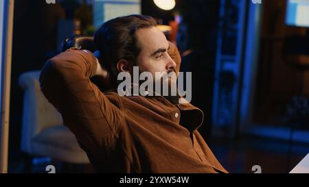 Happy computer scientist feeling relieved, finally being able to relax after removing all code bugs. Joyful IT professional pleased after solving script errors, lounging on desk chair Stock Photo