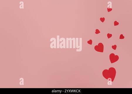 Red paper hearts scattered on a pink background Stock Photo
