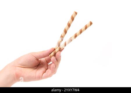 Hand holds striped chocolate wafer rolls. White background. Stock Photo