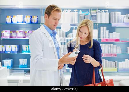 Pharmacy, man and woman with cosmetics, advice and reading instructions on skincare bottle together in shop. Dermatology, pharmacist and customer with Stock Photo