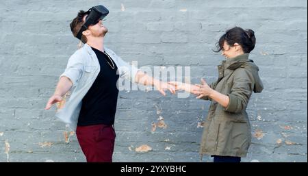 Couple, vr and headset in street with game, laughing and guide for rpg with futuristic tech in city. Woman, man and happy with augmented reality Stock Photo