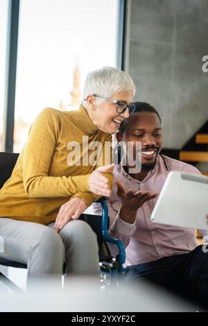 Diverse business colleagues collaborating. Woman in wheelchair working in inclusive office, teamwork Stock Photo