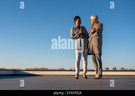 Two diverse business woman holding cup of coffee outdoors. Business woman talking for business plan Stock Photo