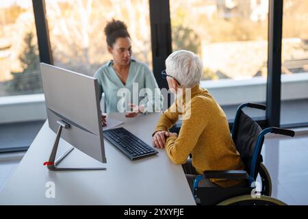 The image includes a person using a wheelchair, depicting inclusivity and teamwork in modern office Stock Photo