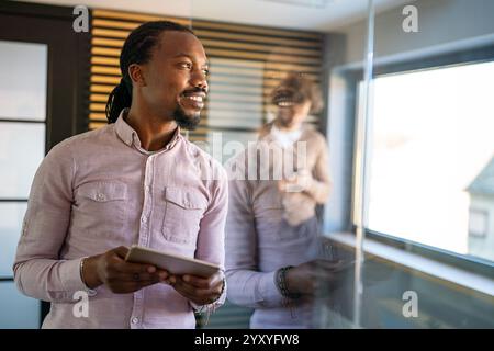 Smiling busy young African American business man, manager using tablet computer Stock Photo