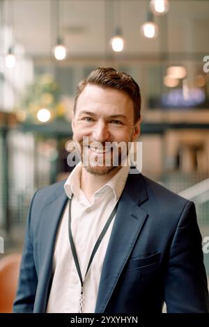 Portrait of smiling male entrepreneur in blazer at convention center Stock Photo