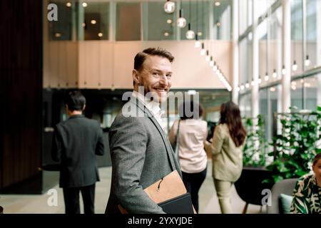 Side view portrait of smiling male entrepreneur in lobby at convention center Stock Photo