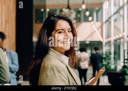 Side view portrait of smiling businesswoman with long hair at convention center Stock Photo