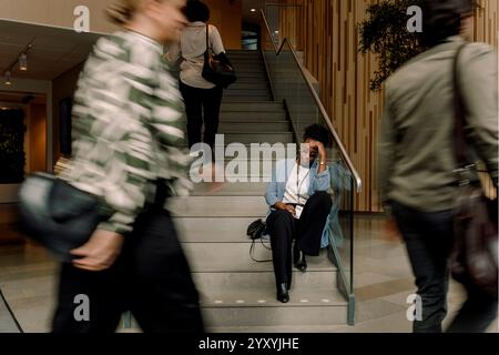 Stressed businesswoman sitting on steps at convention center Stock Photo