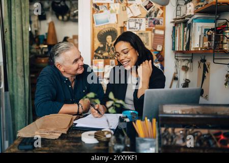 Smiling female colleague talking with senior male owner while working at antique shop Stock Photo