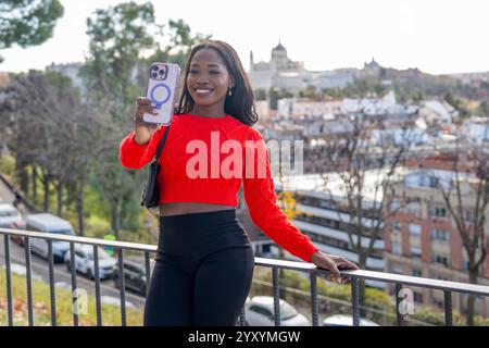 Young woman taking pictures with her smartphone in madrid city center with the almudena cathedral in the background Stock Photo