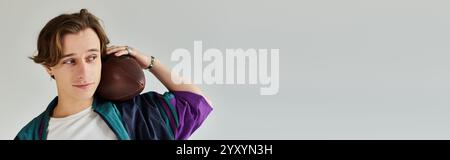 A handsome young man poses in a studio wearing a trendy bomber jacket, showcasing youth culture. Stock Photo