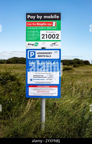 Pay-by-Mobile parking sign, a pay station sign situated in a grassy field, serving as a parking payment kiosk Stock Photo