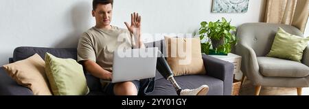 Handsome young man using a laptop to video chat while sitting comfortably at home Stock Photo