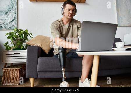Young handsome man using laptop at home, wearing headphones, focused and engaged in work. Stock Photo