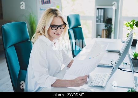 Photo of broker lady working with documents holding paper data diagrams charts analyzing summary sales at office workplace Stock Photo