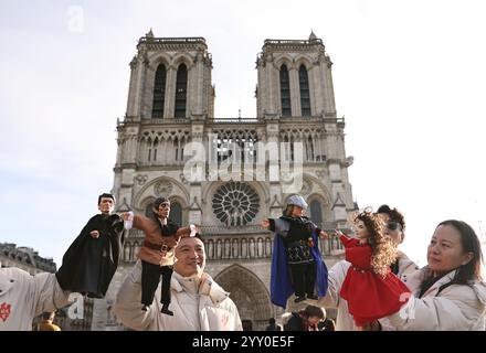 Paris, France. 15th Dec, 2024. Chinese actors perform a hand-puppet theater play 'Notre-Dame de Paris' in front of the Notre-Dame de Paris cathedral, in Paris, France, Dec. 15, 2024. Chinese actors staged a flash mob performance of hand-puppet theater play 'Notre-Dame de Paris' in front of the newly reopened Notre-Dame de Paris cathedral, as part of the Chinese Tour in France's Most Beautiful Villages, an event designed to boost Franco-Chinese cultural exchanges. Credit: Gao Jing/Xinhua/Alamy Live News Stock Photo