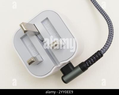 Closeup isolated shot of a UK British electric travel plug and cable or cord, with 3 protruding pins which fold flat when not in use. Stock Photo