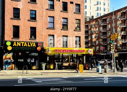 NEW YORK, NY, USA - DECEMBER 13, 2024: Brightly lit storefronts showcase diverse convenience and dining options in the Chelsea neighborhood, bustling Stock Photo