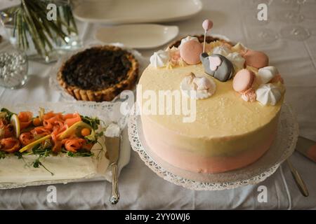 Christening cake decorated with marshmallows and macaroons and elefant on the table. Stock Photo