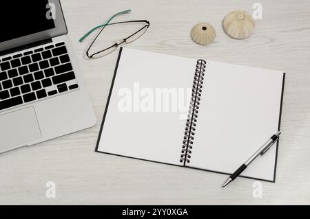 blank page of notebook on table with glasses and laptop Stock Photo
