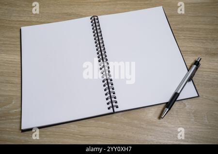 an opened blank page of a notebook with a pen on the table Stock Photo