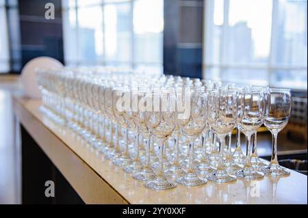 Many empty wine glasses line up waiting to pour some liquor for many invitation guests in the dinner reception celebration party in a lounge in the ho Stock Photo