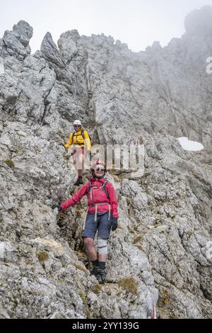 Two mountaineers with helmets climbing on a rock face, ascent to the Ackerlspitze, Wilder Kaiser, Kaiser Mountains, Tyrol, Austria, Europe Stock Photo