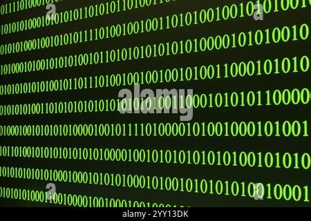 Green binary code arranged in rows on a black background Stock Photo