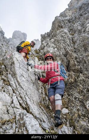 Two mountaineers with helmets climbing on a rock face, ascent to the Ackerlspitze, Wilder Kaiser, Kaiser Mountains, Tyrol, Austria, Europe Stock Photo