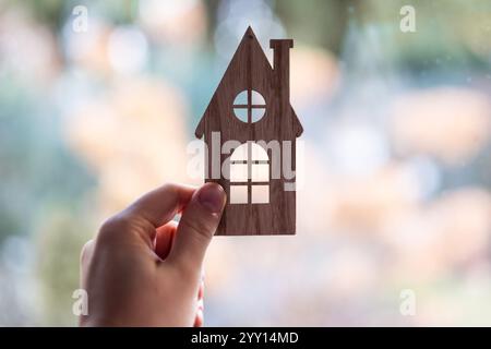 human hand holding a representation of a wooden dream house against nature background Stock Photo