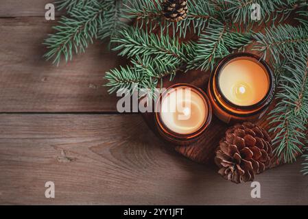 Scented candles and fir tree braches on wooden background, top view, copy space. Birning candle with pine, winter Christmas holiday, hygge and aroma s Stock Photo