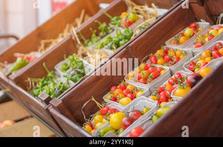 Local fresh organic tomatoes and peppers displayed in wooden crates. Small business farmers selling healthy produce at the market. Healthy food concep Stock Photo