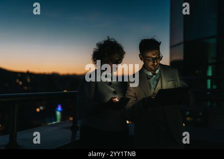 Business people collaborating outside during evening hours under city lights Stock Photo